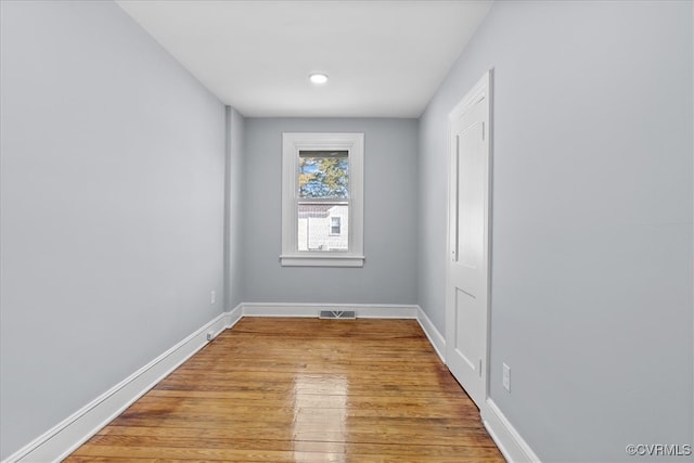 empty room featuring visible vents, baseboards, and wood finished floors