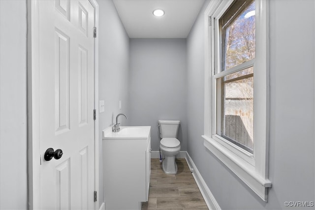 bathroom with baseboards, vanity, toilet, and wood finished floors