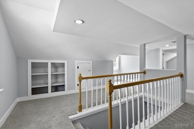 corridor featuring lofted ceiling, carpet, built in features, and baseboards