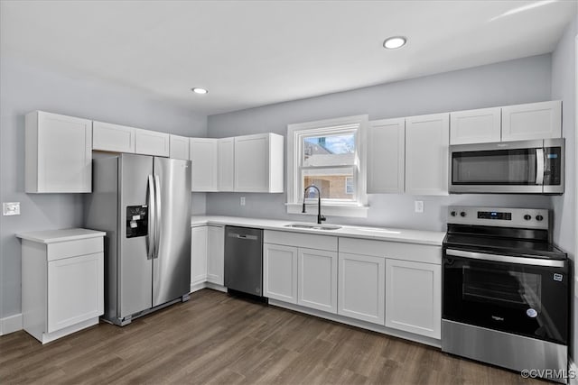 kitchen with stainless steel appliances, light countertops, dark wood-type flooring, white cabinetry, and a sink