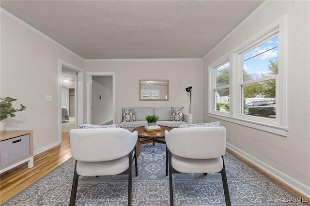 living area featuring crown molding, baseboards, and wood finished floors