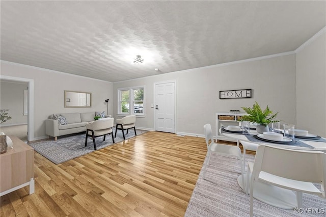 living room with light wood-style floors, crown molding, a textured ceiling, and baseboards