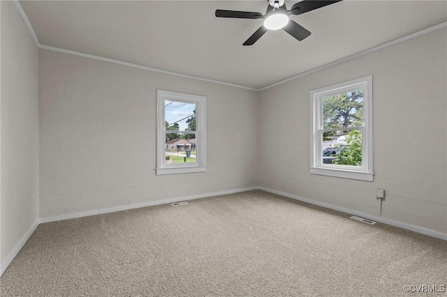 carpeted spare room with a healthy amount of sunlight, baseboards, ornamental molding, and ceiling fan