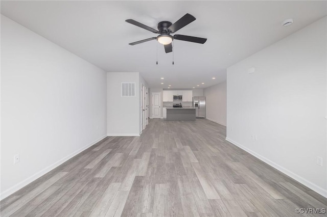 unfurnished living room with light wood-style flooring, a ceiling fan, visible vents, and baseboards