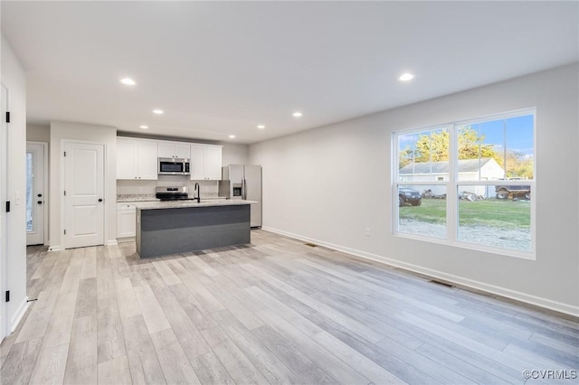 kitchen featuring light wood-style flooring, recessed lighting, white cabinets, appliances with stainless steel finishes, and an island with sink