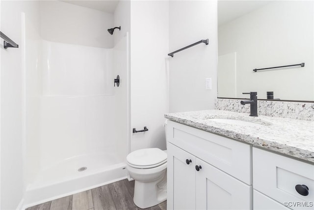 bathroom with wood finished floors, a stall shower, vanity, and toilet