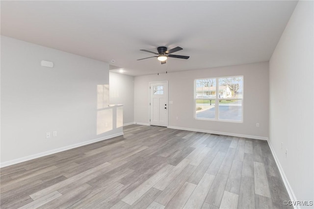 unfurnished living room with ceiling fan, light wood-style flooring, and baseboards