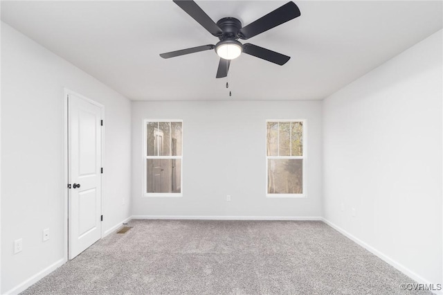 empty room featuring a ceiling fan, light colored carpet, and baseboards