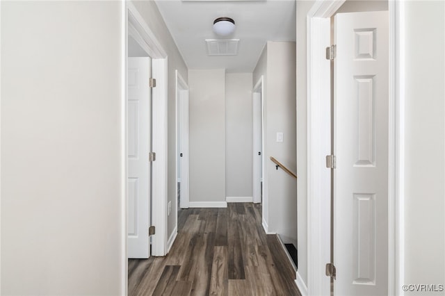 corridor with baseboards, visible vents, and dark wood-type flooring