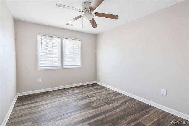 spare room with a ceiling fan, dark wood finished floors, visible vents, and baseboards