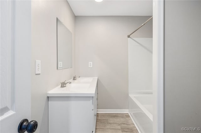 full bathroom featuring double vanity, bathtub / shower combination, and baseboards