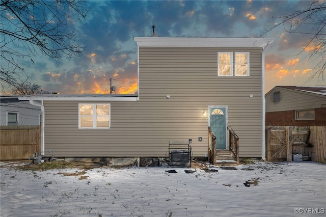 snow covered property featuring entry steps, fence, and cooling unit