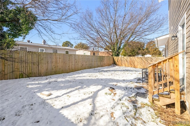 yard layered in snow featuring a fenced backyard