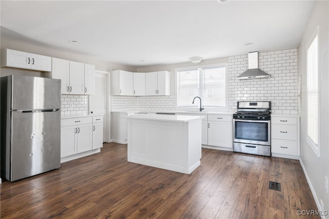 kitchen featuring stainless steel appliances, dark wood-style flooring, white cabinetry, light countertops, and wall chimney exhaust hood