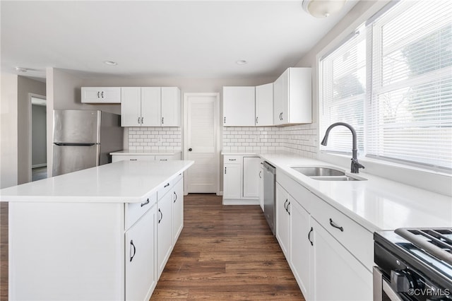 kitchen featuring a kitchen island, appliances with stainless steel finishes, light countertops, white cabinetry, and a sink