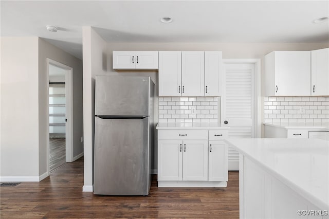 kitchen with freestanding refrigerator, dark wood-style flooring, light countertops, and white cabinetry