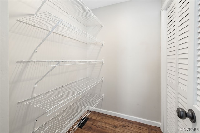 walk in closet with dark wood-style flooring