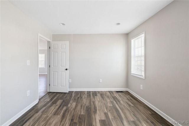 unfurnished room with dark wood-style floors, plenty of natural light, and baseboards