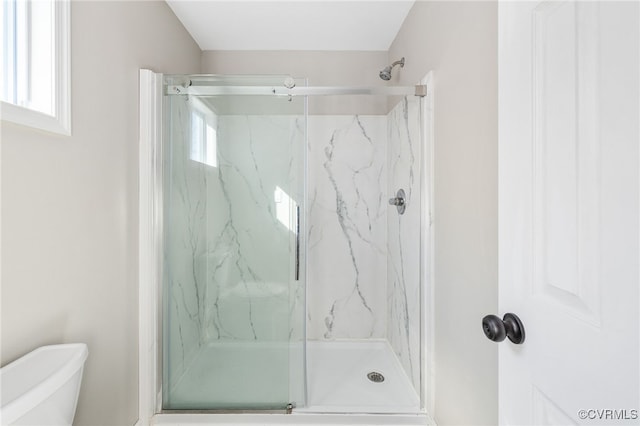 bathroom with toilet and a marble finish shower