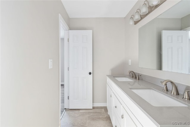 full bath with double vanity, a sink, and baseboards