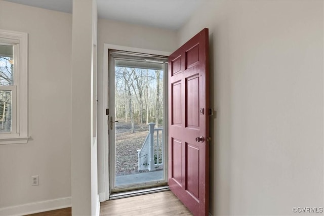 doorway to outside with light wood-style flooring and baseboards