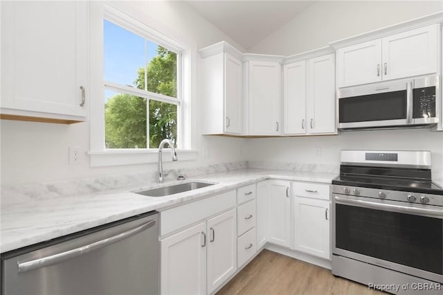 100 Bowsprit Ln, Wicomico Church, VA 22473 - kitchen with stainless steel appliances, white cabinets, vaulted ceiling, light wood-type flooring, and light stone counters