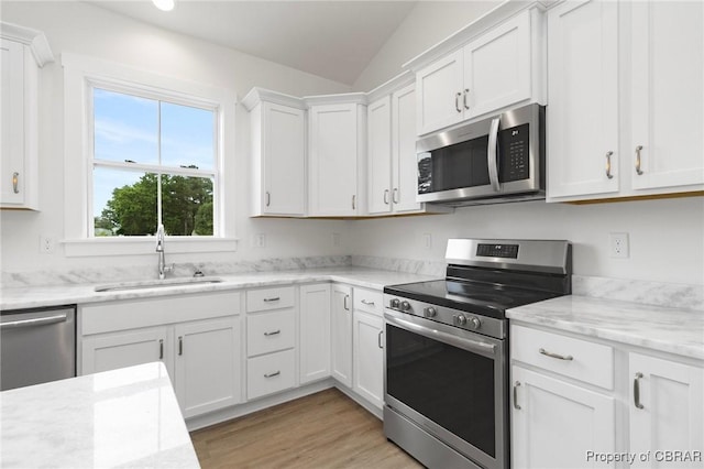 100 Bowsprit Ln, Wicomico Church, VA 22473 - kitchen featuring stainless steel appliances, white cabinets, vaulted ceiling, light wood-style floors, and light stone countertops