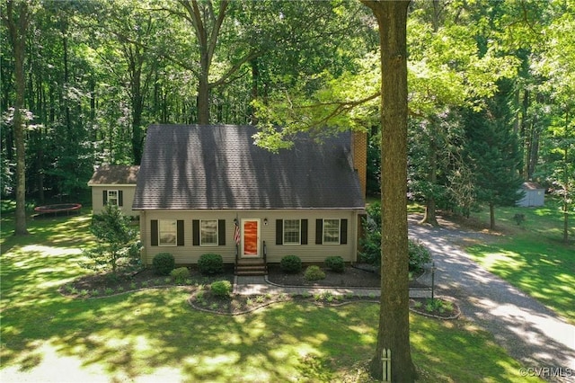 cape cod home featuring entry steps, a front lawn, a trampoline, and a chimney