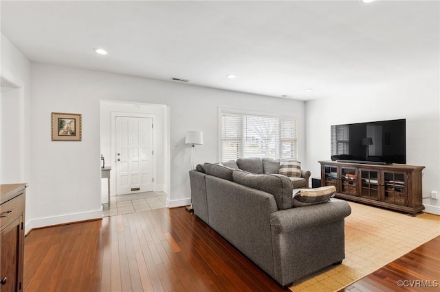 living room featuring recessed lighting, dark wood-style flooring, visible vents, and baseboards