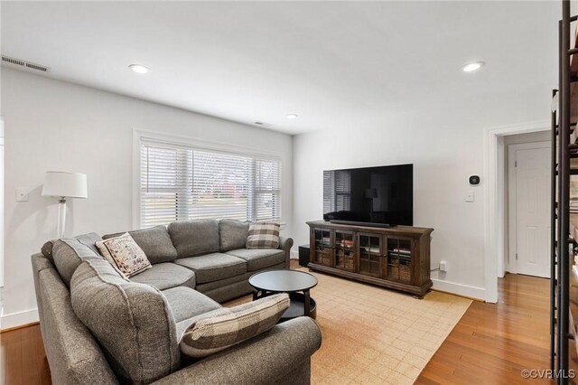 living room featuring light wood-type flooring, baseboards, visible vents, and recessed lighting