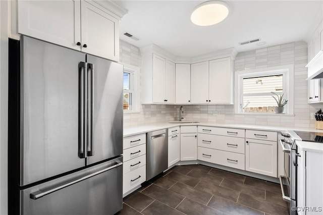 kitchen with appliances with stainless steel finishes, visible vents, a sink, and backsplash