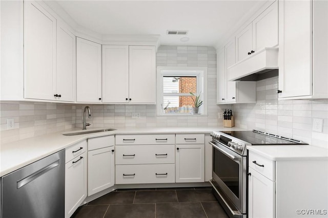 kitchen with dark tile patterned flooring, a sink, visible vents, appliances with stainless steel finishes, and custom range hood