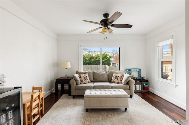 living room with ceiling fan, wine cooler, wood finished floors, and baseboards