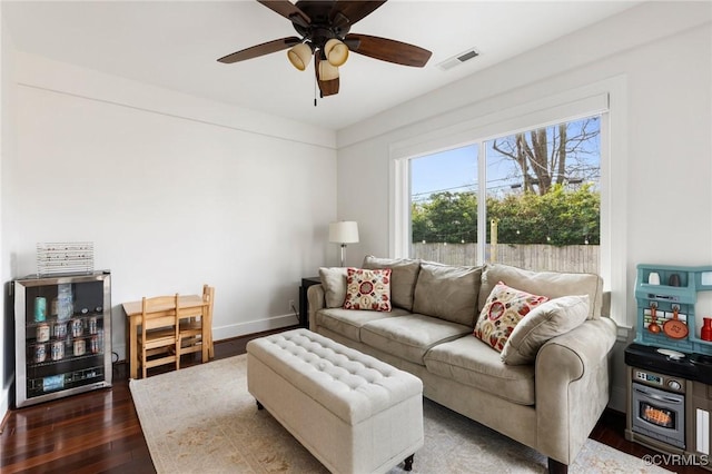 living room with baseboards, visible vents, dark wood finished floors, and a ceiling fan