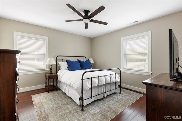 bedroom with ceiling fan, visible vents, baseboards, and dark wood-style flooring