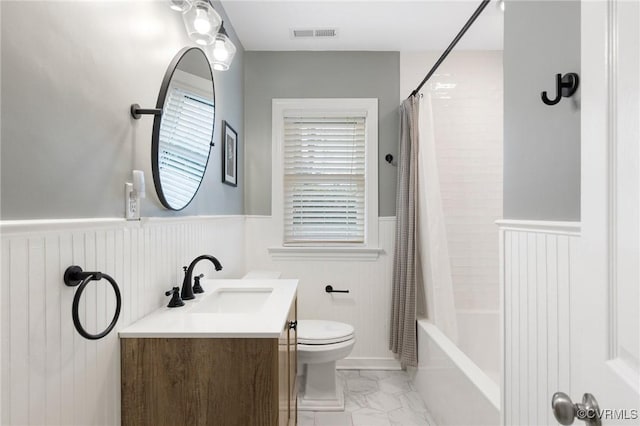 bathroom featuring toilet, vanity, visible vents, marble finish floor, and wainscoting