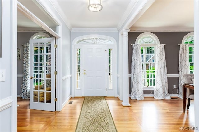 foyer featuring decorative columns, visible vents, baseboards, ornamental molding, and light wood-style floors