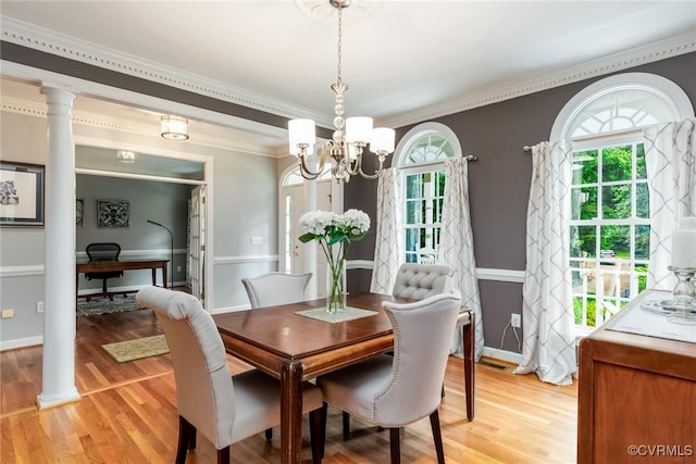 dining space with light wood-type flooring, ornate columns, a notable chandelier, and crown molding