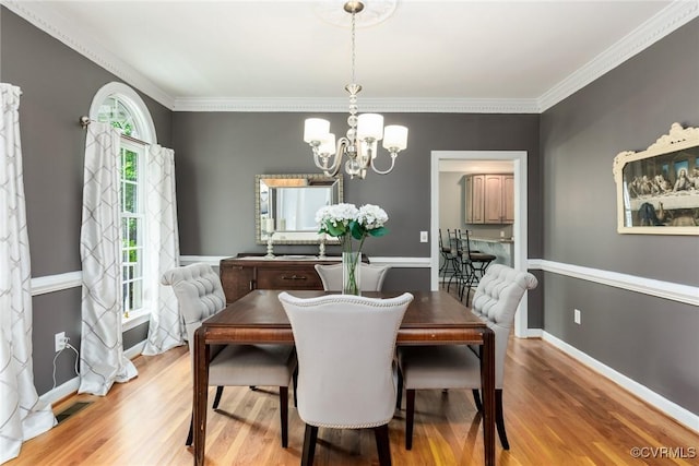 dining room with crown molding, an inviting chandelier, wood finished floors, and baseboards