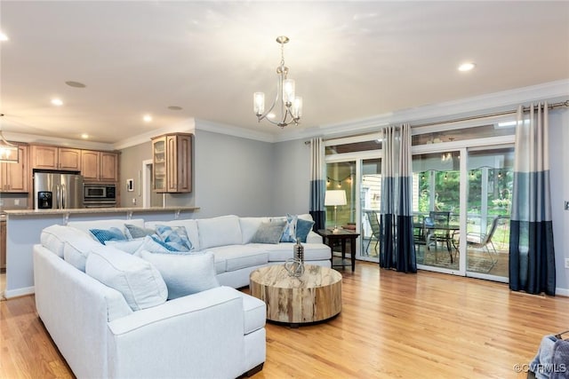 living area with light wood finished floors, recessed lighting, ornamental molding, and an inviting chandelier