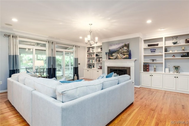 living room featuring ornamental molding, a chandelier, light wood-type flooring, baseboards, and a tile fireplace