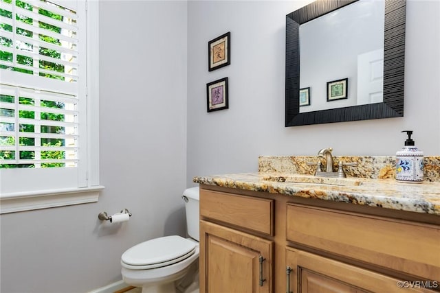 half bathroom featuring baseboards, vanity, and toilet