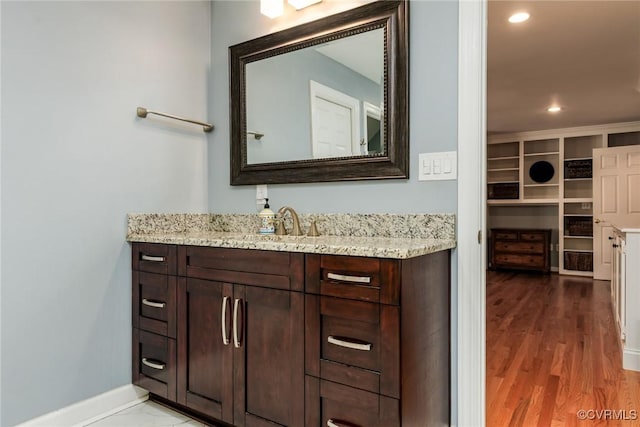 bathroom with recessed lighting, wood finished floors, vanity, and baseboards