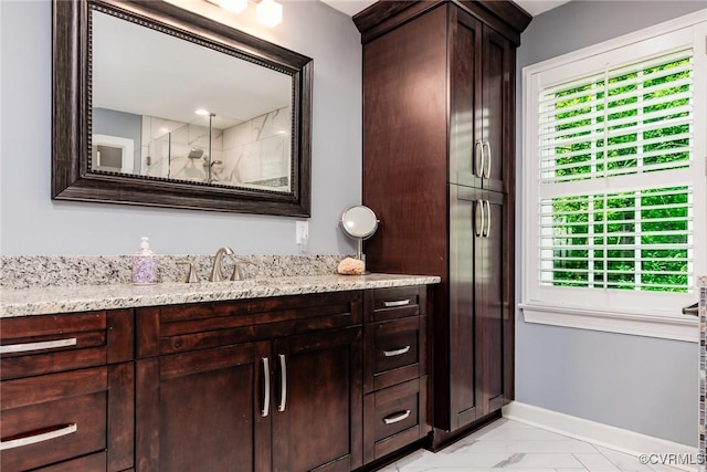 bathroom with marble finish floor, vanity, and baseboards