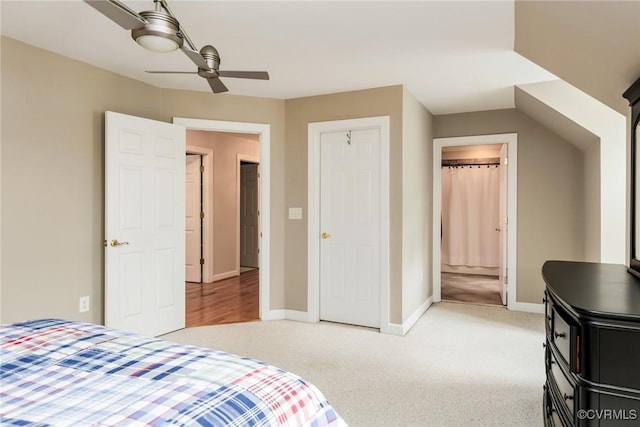 bedroom featuring ensuite bath, baseboards, a ceiling fan, and light colored carpet