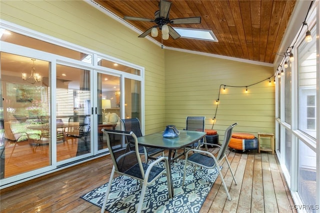 sunroom with ceiling fan with notable chandelier, vaulted ceiling with skylight, plenty of natural light, and wood ceiling