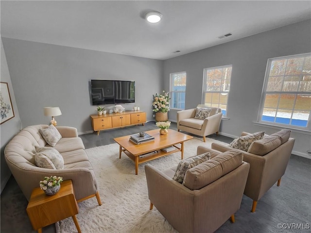 living area featuring a wealth of natural light, visible vents, and baseboards