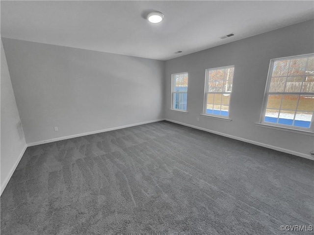 unfurnished room featuring dark colored carpet, visible vents, and baseboards