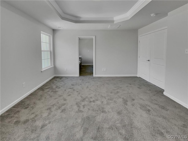 unfurnished bedroom featuring carpet, baseboards, and a raised ceiling