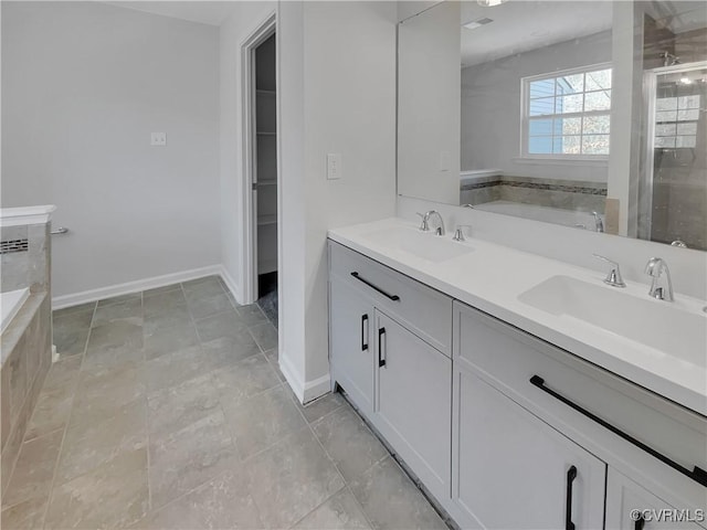 bathroom featuring double vanity, a spacious closet, baseboards, and a sink